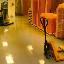 A yellow pallet truck in an industrial warehouse.