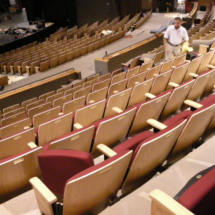 A man is standing in an auditorium with rows of seats.