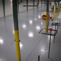 A warehouse with yellow poles and white floors.