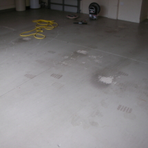 A white tile floor with yellow hose and black wheels.