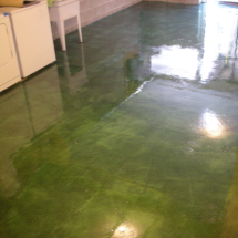 A kitchen with green stained concrete floors.