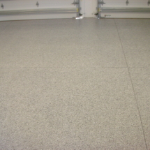 A garage floor with white speckles and some metal bars
