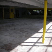 A yellow pole in an empty room with windows.
