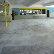 A large empty room with yellow poles and concrete floors.