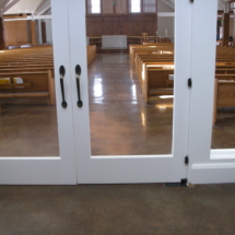 A church with two doors open and benches in the background.