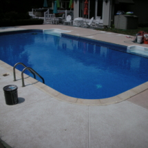 A pool with a blue water and a white deck