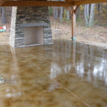 A patio with a fireplace and concrete floor.