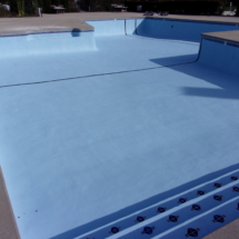 A pool with blue water and black tiles on the bottom.
